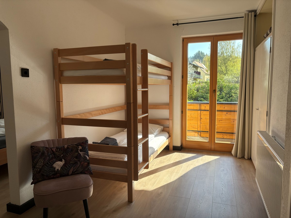 Afbeelding van Comfortable familiekamer met balkon en tuinzicht.