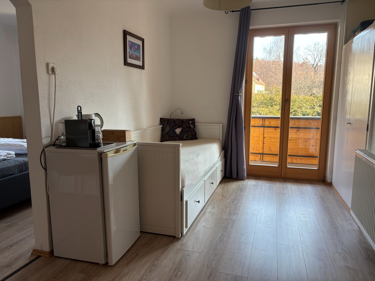 Afbeelding van Comfortable familiekamer met balkon en tuinzicht.