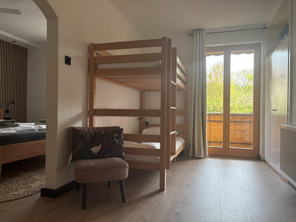 Afbeelding van Comfortable familiekamer met balkon en tuinzicht.