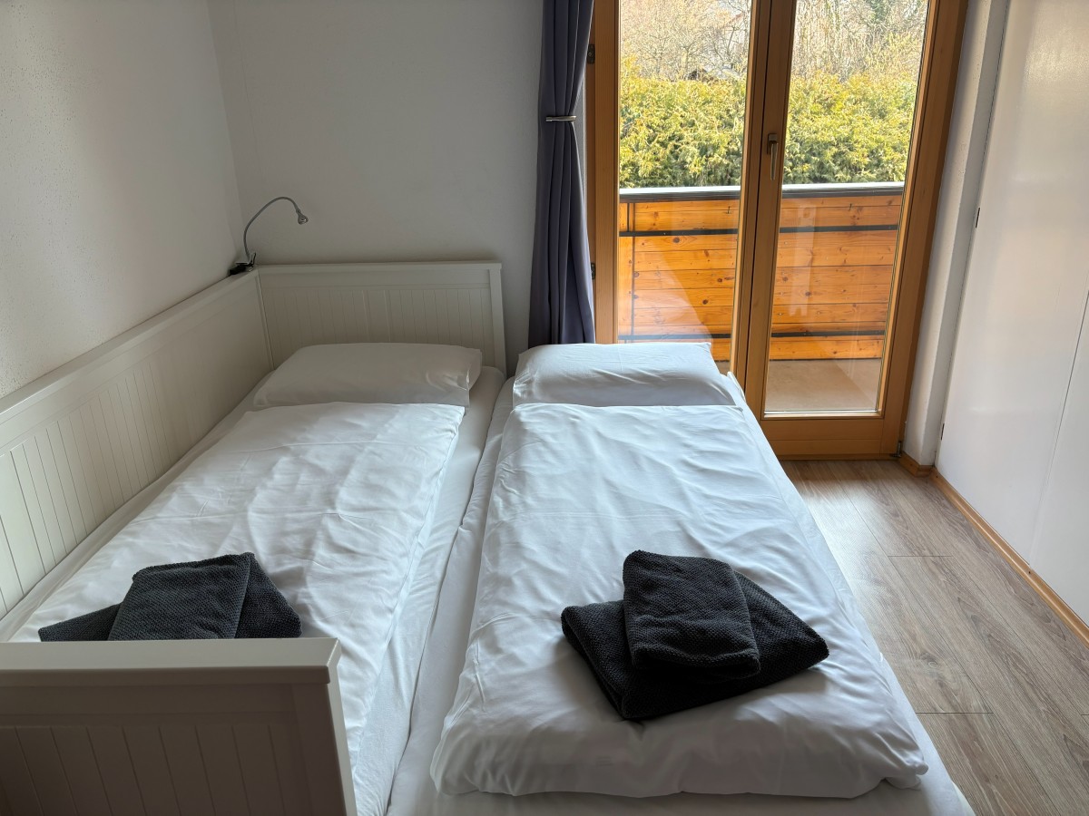 Afbeelding van Comfortable familiekamer met balkon en tuinzicht.